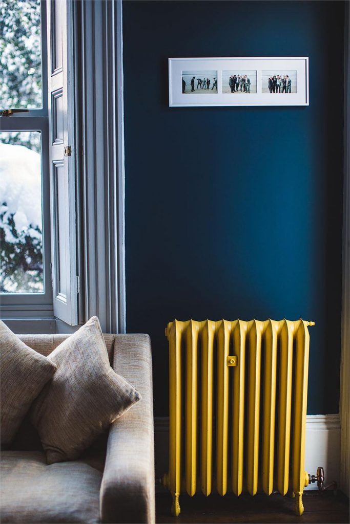 Radiator in front of blue wall and sofa