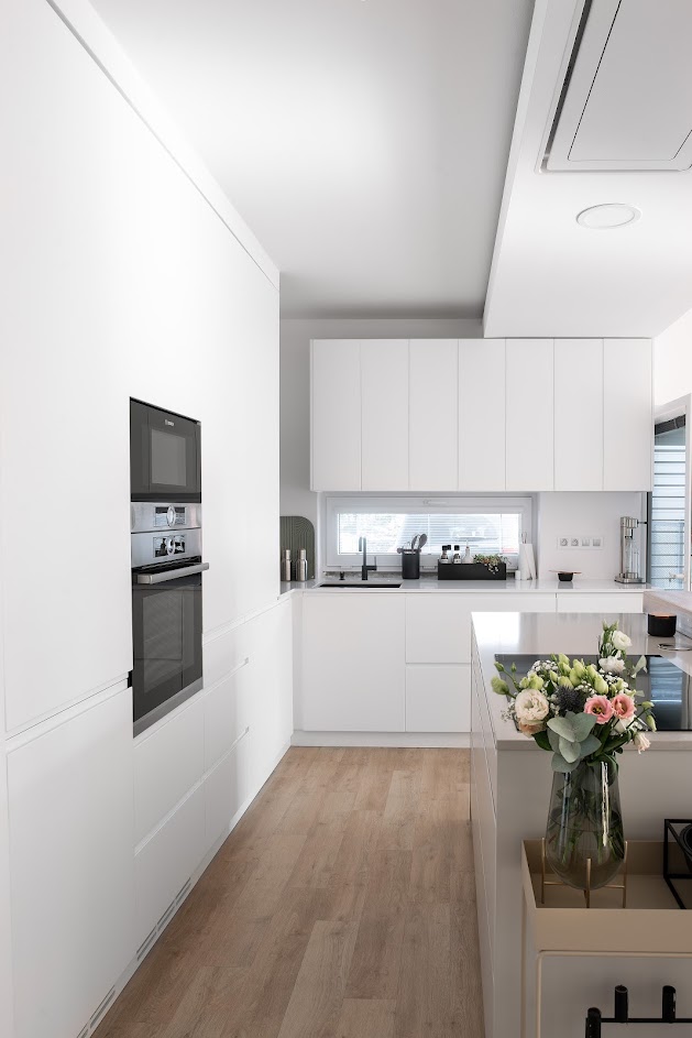 The kitchen area is dominated by a block with storage space and built-in appliances. TechniStone® Crystal Absolute White